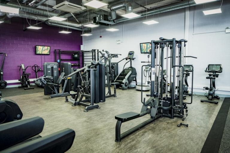 Image shows gym floor layout with a range of cardio and weights machines. 