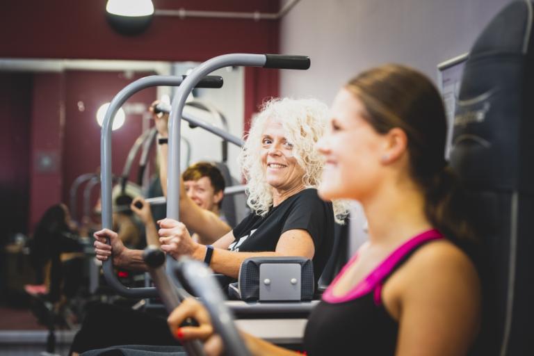 Image shows three women in the distance, each sitting on a different toning machine.