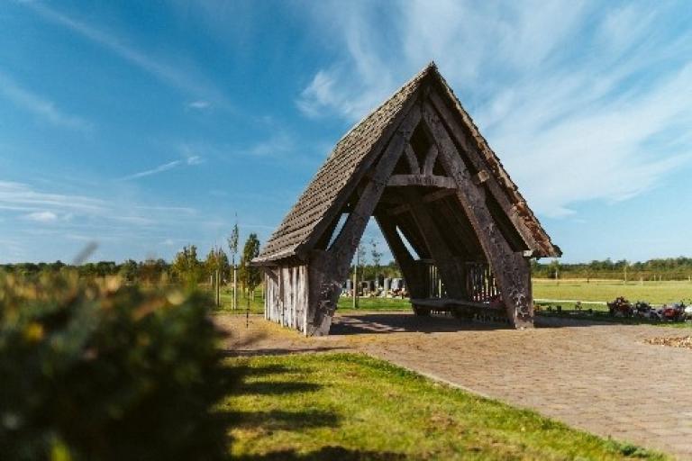 Wooden shelter at Strawberry Lane Cemetery with blue skies and white clouds with path and grass in foreground