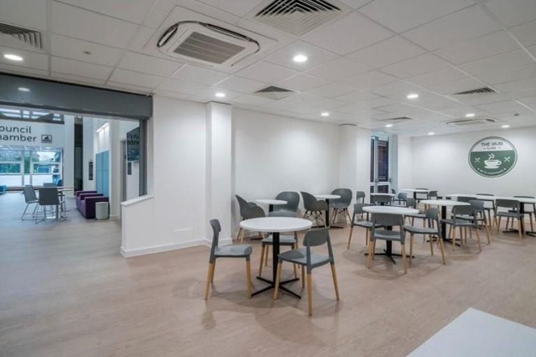 Image show spacious, clean and fresh cafe area with white tables and chairs.