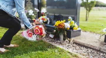 A woman lays a bouquet at a grave in Strawberry Lane Cemetery, Great Wyrley