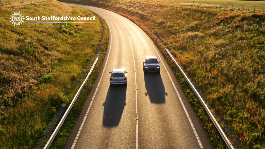 Two cars driving down a road