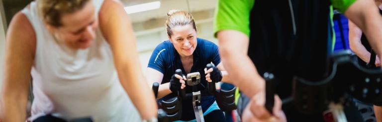 Image shows small group of people on indoor cycling bikes. 