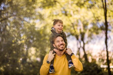 Boy sits on father's shoulders as they walk through the countryside